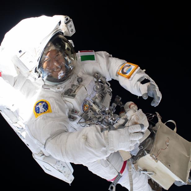 Ein Astronaut mit der ungarischen Flagge auf dem Anzug arbeitet im Weltraum.