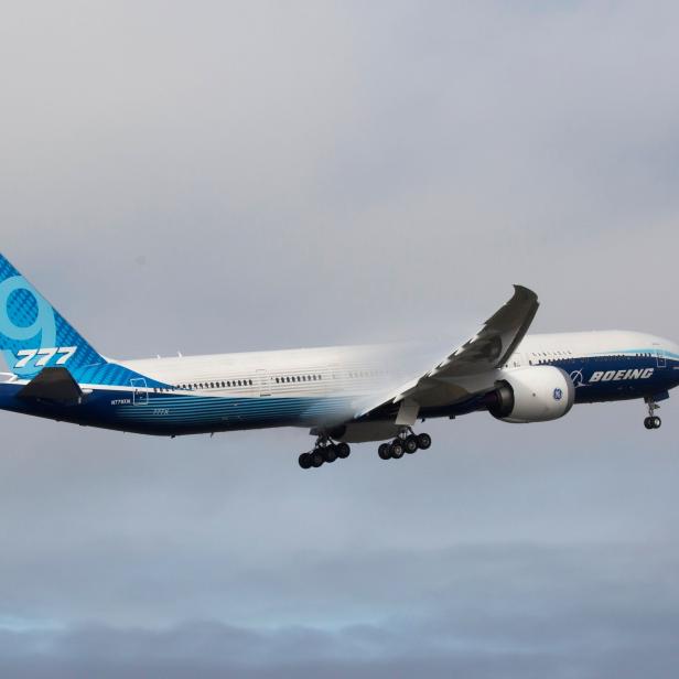 Eine Boeing 777X im Landeanflug vor einem bewölkten Himmel.
