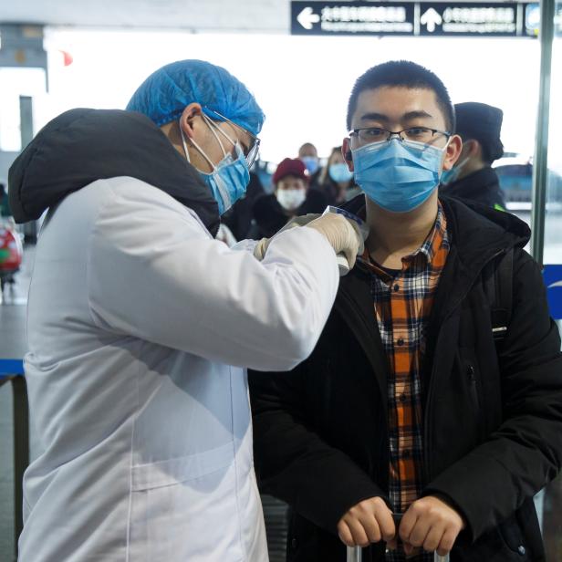 A medical official takes the body temperature of a man at the departure hall of the airport in Changsha