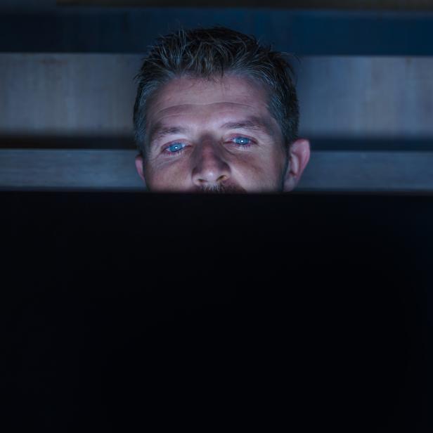 young attractive and relaxed internet addict man networking concentrated late at night on bed with laptop computer in social media addiction or workaholic businessman concept