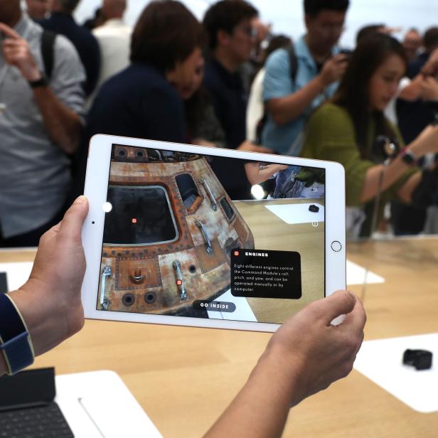 Eine Person betrachtet auf einem iPad eine Augmented-Reality-Ansicht der Apollo-Kapsel.