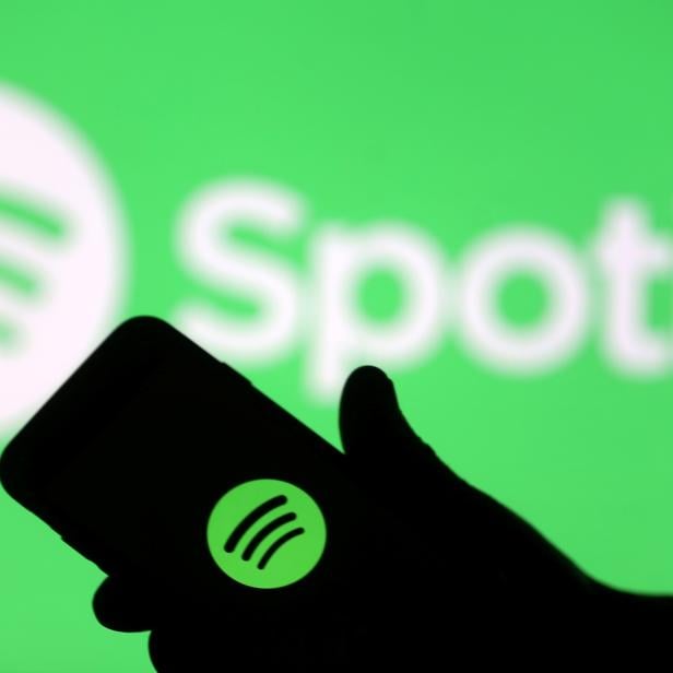 FILE PHOTO: A smartphone is seen in front of a screen projection of Spotify logo, in this picture illustration