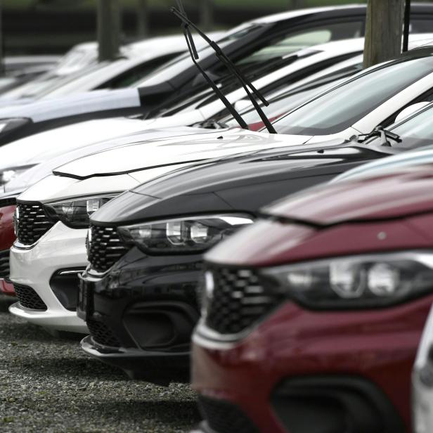 Eine Reihe neuer Autos unterschiedlicher Farben stehen auf einem Parkplatz.
