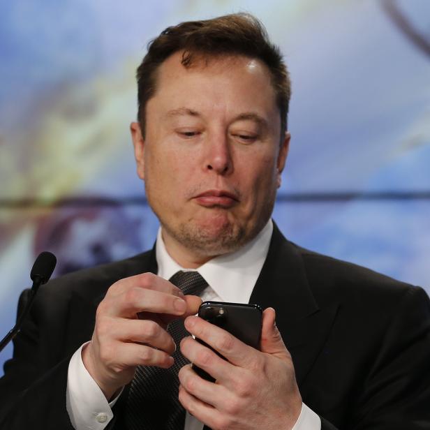 SpaceX founder and chief engineer Elon Musk looks at his mobile phone during a post-launch news conference to discuss the  SpaceX Crew Dragon astronaut capsule in-flight abort test at the Kennedy Space Center