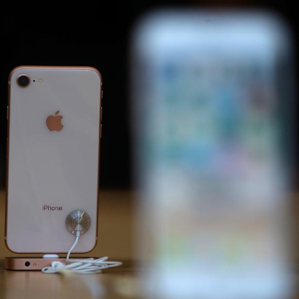 Ein iPhone mit Kopfhörern auf einem Tisch.