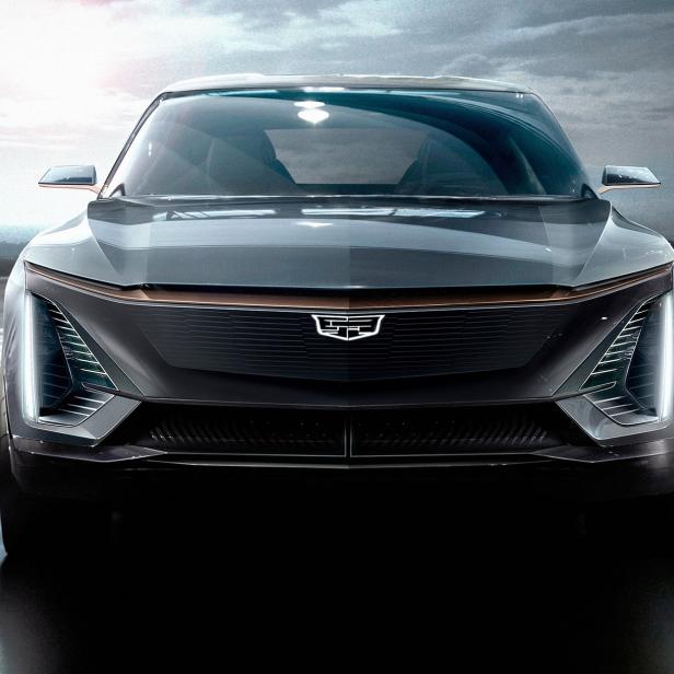 Die Frontansicht eines grauen Cadillac Lyriq Elektroautos in einem Ausstellungsraum.