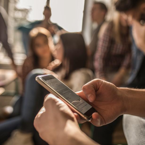 Close up of unrecognizable student using cell phone on a break in the classroom.