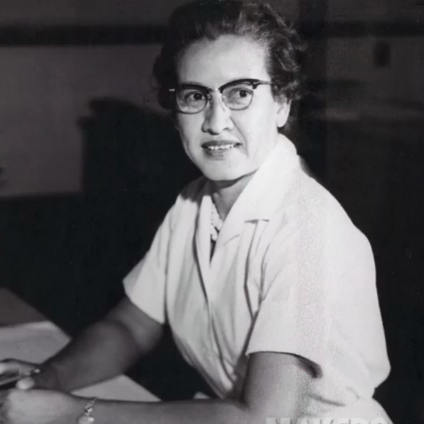 Katherine Johnson sitzt an einem Schreibtisch mit einer Weltkugel und einer Rechenmaschine.