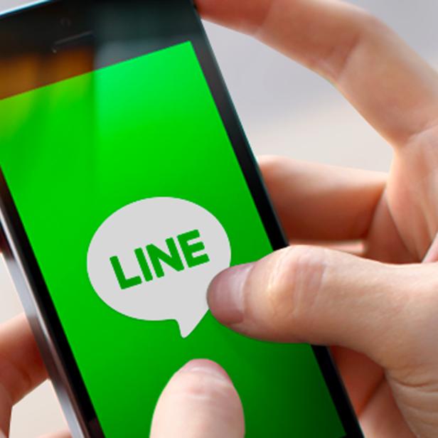 Eine Person hält ein Smartphone mit dem Logo der Messaging-App LINE auf dem Bildschirm.