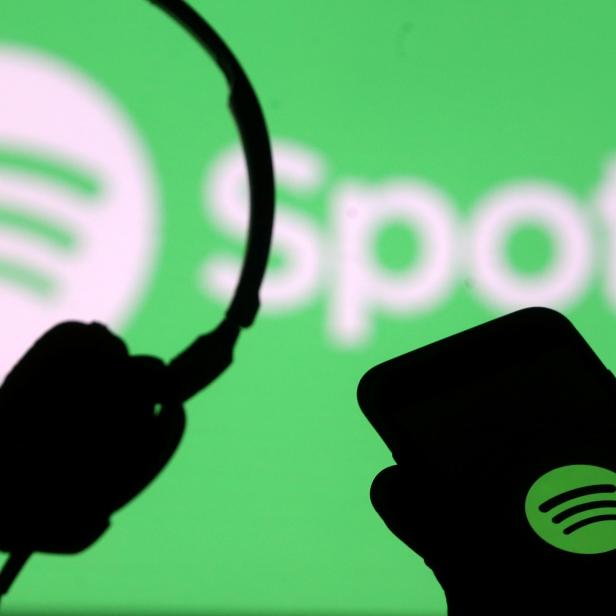 FILE PHOTO: A smartphone and a headset are seen in front of a screen projection of Spotify logo, in this picture illustration