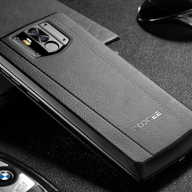 Ein robustes Doogee-Smartphone mit Lederstruktur liegt auf einem Tisch.