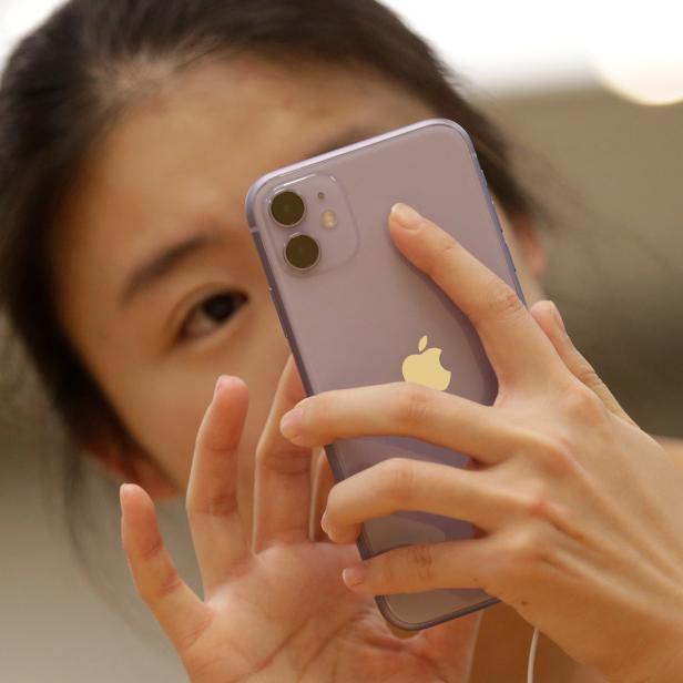 A customer tests Apple's new iPhone 11 after it went on sale at the Apple Store in Beijing