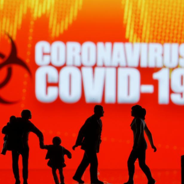 Small toy figures are seen in front of the coronavirus (COVID-19) sign in this illustration taken