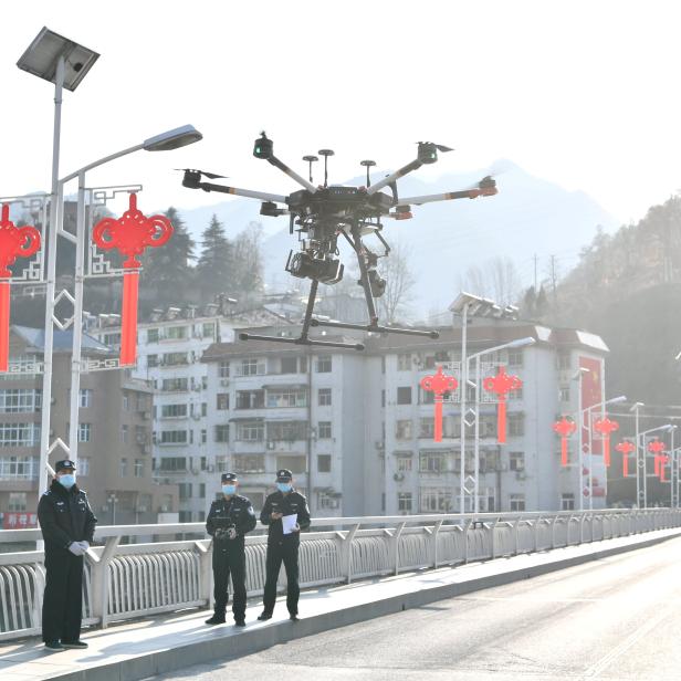 Police officers operate a drone to spread information about the prevention and control of the new coronavirus, in Baokang