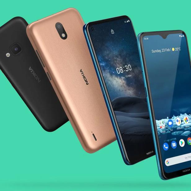 Vier Nokia-Smartphones in verschiedenen Farben vor einem türkisfarbenen Hintergrund.