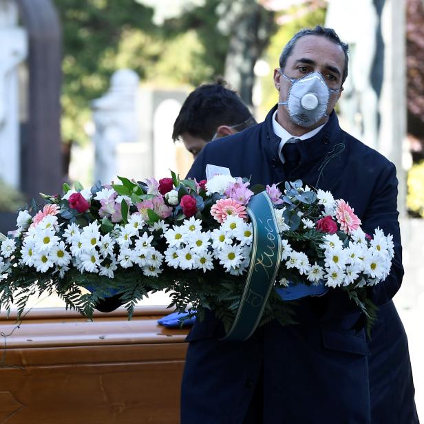 Cemetery workers and funeral agency workers in protective masks transport a coffin of a person who died from coronavirus disease (COVID-19), into a cemetery in Bergamo