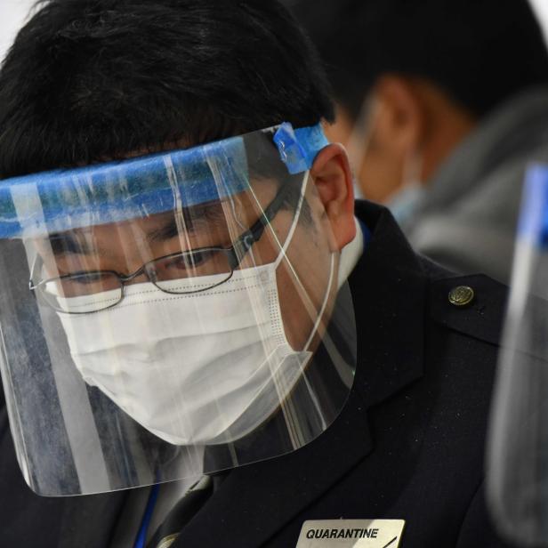 Ein Mann mit Gesichtsmaske und Schutzvisier, möglicherweise im Zusammenhang mit Quarantänebestimmungen in Japan.