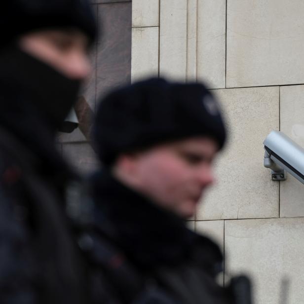 FILE PHOTO: Police officers walk past a CCTV camera in central Moscow