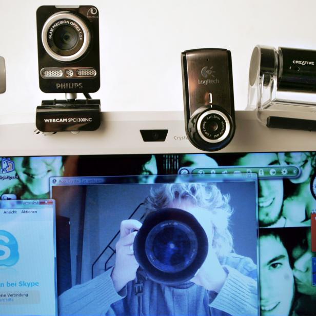 Mehrere Webcams verschiedener Marken stehen auf einem Laptop, der Skype und ein Webcam-Bild anzeigt.
