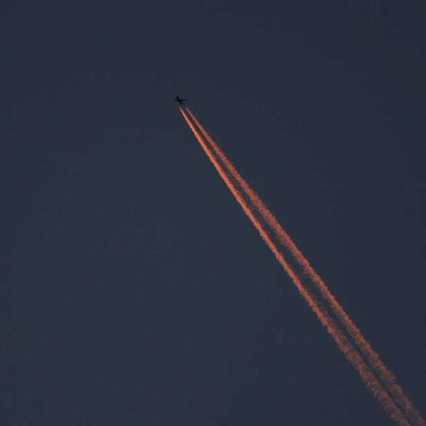 A passenger plane leaves behind contrails as it flies in the skies over London Luton Airport, Luton