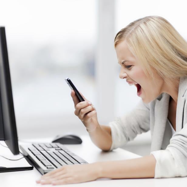 angry woman with smart phone and computer screaming curses