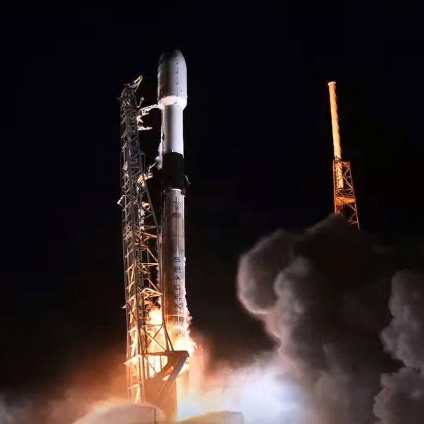 Eine SpaceX-Rakete startet bei Nacht mit einer Wolke aus Rauch und Feuer.