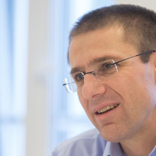Ein Mann mit Brille und blauem Hemd lächelt.