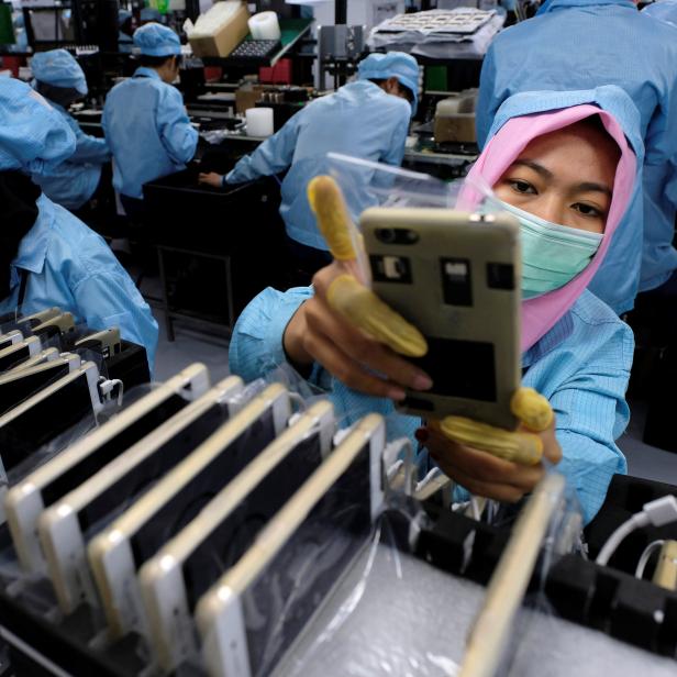 A worker holds an OPPO F1S smartphone at an OPPO smartphone factory in Tangerang