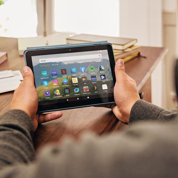 Eine Person hält ein Tablet mit verschiedenen Apps in den Händen.