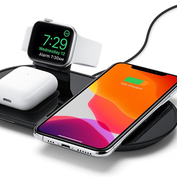 Ein iPhone, eine Apple Watch und AirPods werden kabellos auf einer Ladestation geladen.