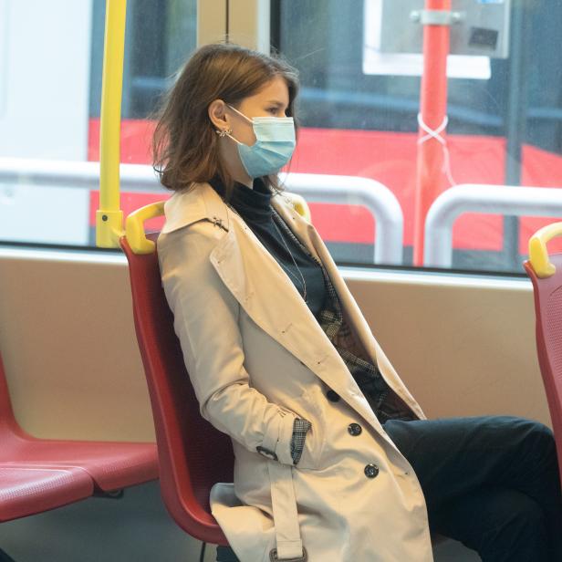 Eine Frau mit medizinischer Maske sitzt in einer U-Bahn.