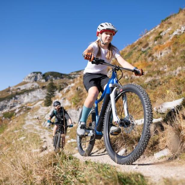Ein junges Mädchen fährt mit einem Mountainbike auf einem Bergpfad.