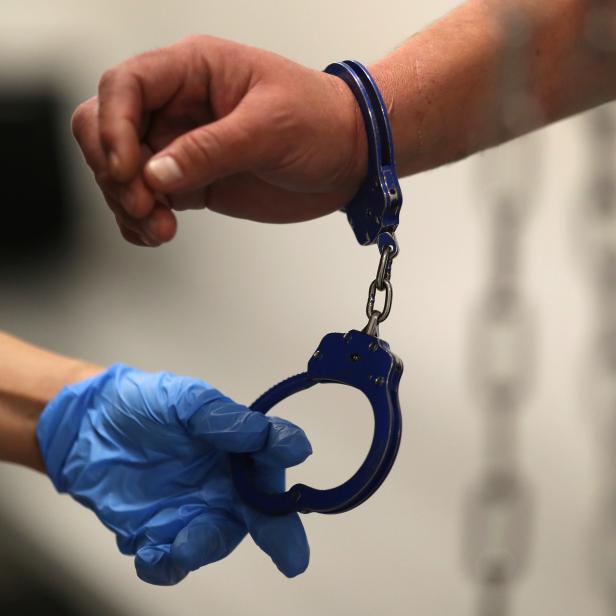 A U.S. Immigration and Customs Enforcement's (ICE) Fugitive Operations Agent takes handcuffs off before booking an immigrant in Los Angeles