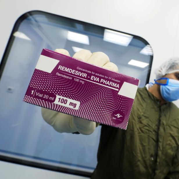 Ein Mitarbeiter in Schutzkleidung hält eine Packung Remdesivir von Eva Pharma in die Kamera.