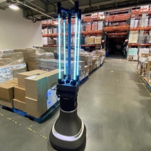 Ein UV-Desinfektionsroboter steht in einem Lagerhaus zwischen Paletten mit Waren.