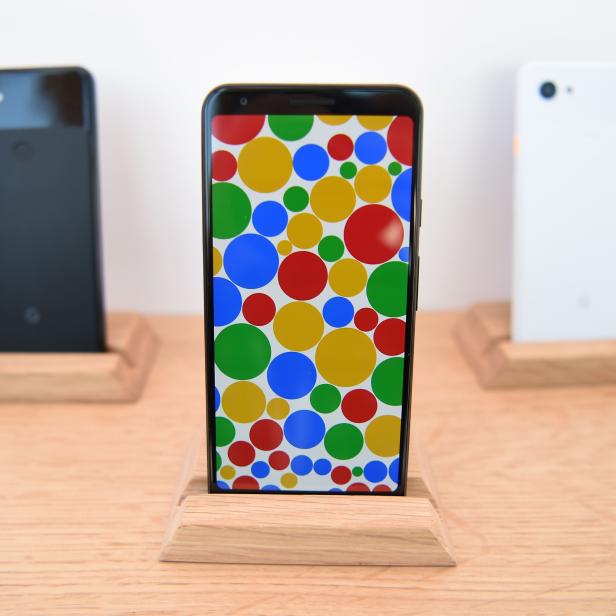 Drei Google Pixel Smartphones stehen auf einem Holztisch.