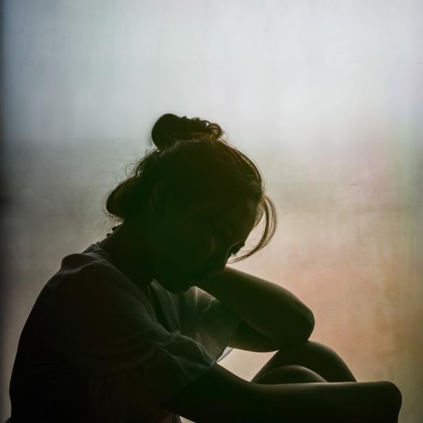 Vintage filtered on silhouette of depressed girl sitting on the window