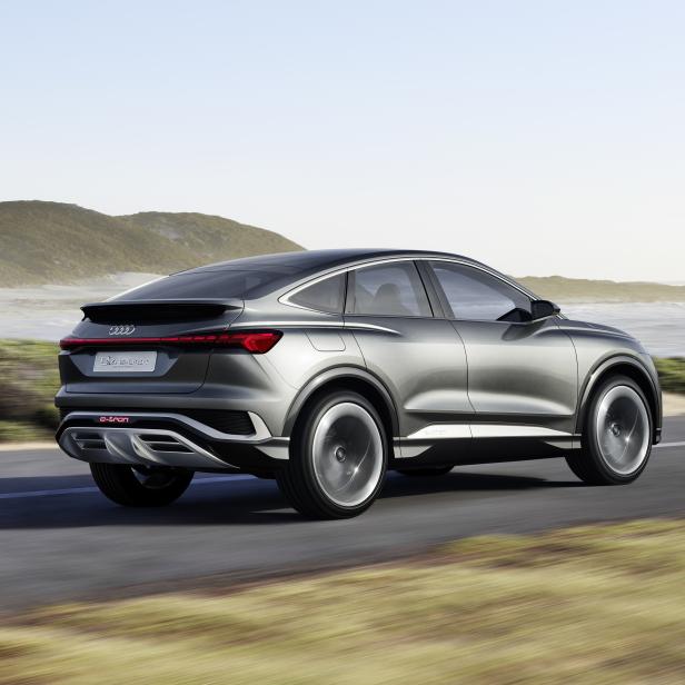 Ein grauer Audi Q4 e-tron fährt auf einer Küstenstraße.