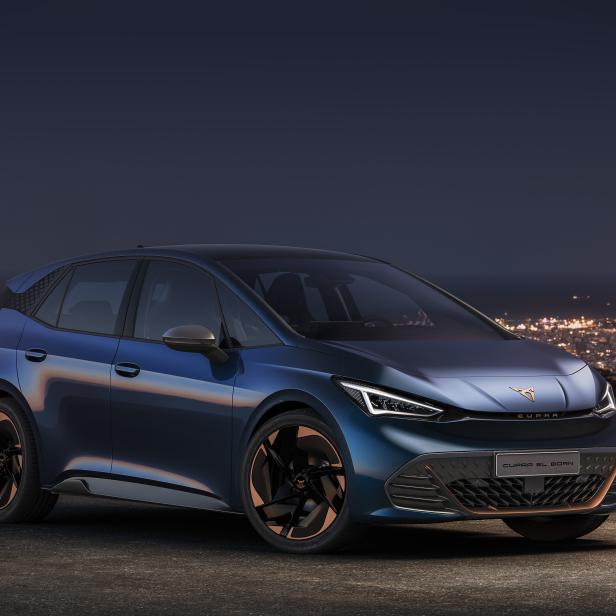 Ein blauer Cupra El-Born vor einer nächtlichen Stadtkulisse.