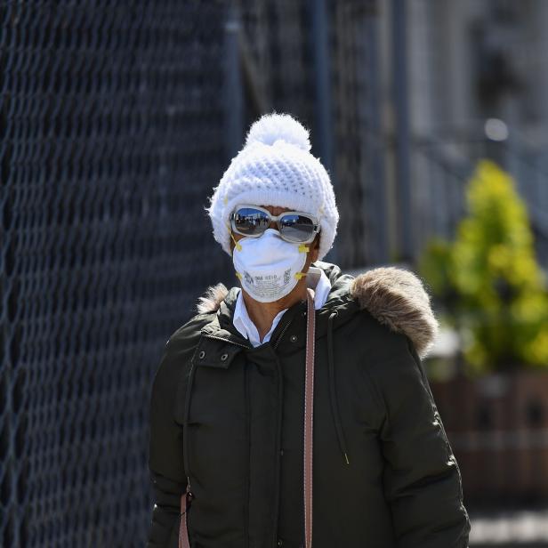 Eine Frau mit Mütze und Maske geht die Straße entlang.