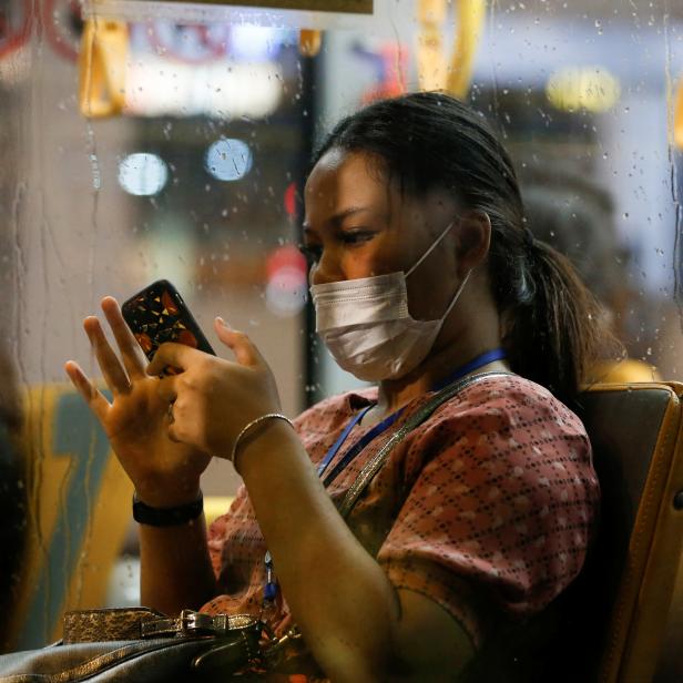 A woman wearing a protective mask uses a smartphone as she travels on a bus during rush hour, after Indonesia confirmed its first cases of COVID-19, in Jakarta