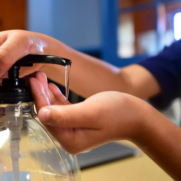 Eine Person benutzt eine Flasche mit Handdesinfektionsmittel.