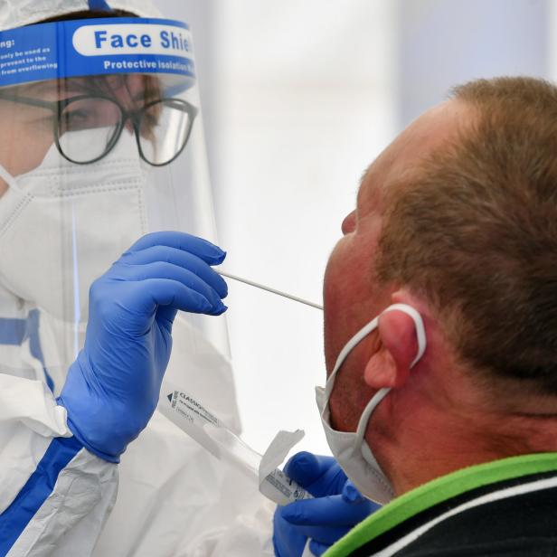Eine medizinische Fachkraft nimmt einen Corona-Abstrich bei einem Mann vor.