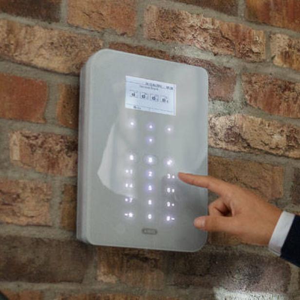Ein Mann bedient ein elektronisches Tastenfeld an einer Ziegelwand.