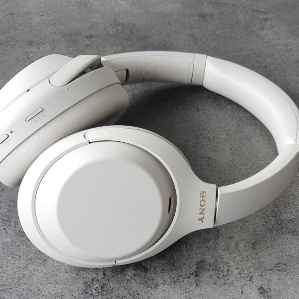 Ein weißer Sony-Kopfhörer liegt auf einer grauen Oberfläche.
