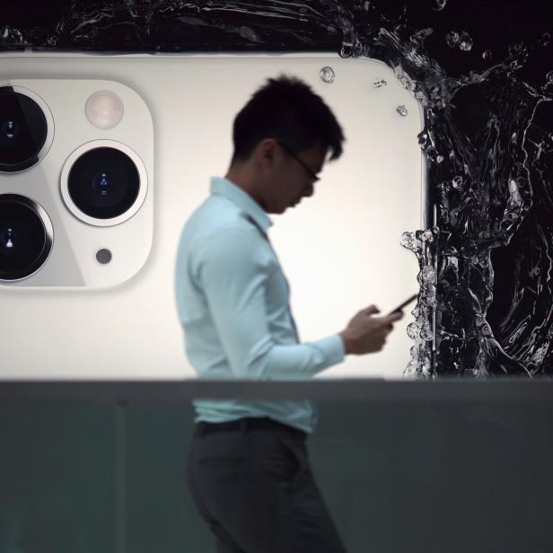 Ein Mann steht vor einem großen Smartphone-Modell, das von Wasser umgeben ist.