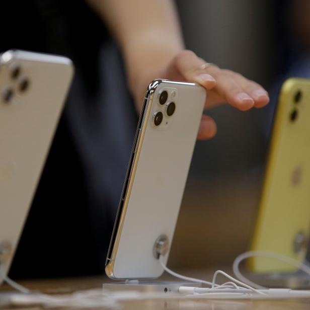 Eine Hand berührt ein weißes iPhone 11 Pro in einem Geschäft.