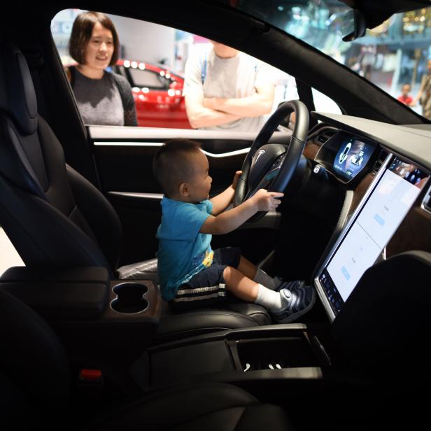 Ein kleiner Junge sitzt am Steuer eines Tesla Model X.