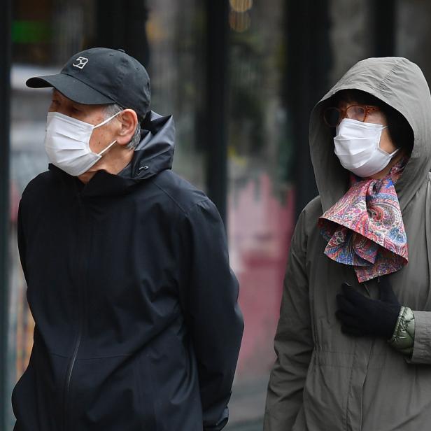 Zwei Personen mit Gesichtsmasken gehen auf der Straße entlang.