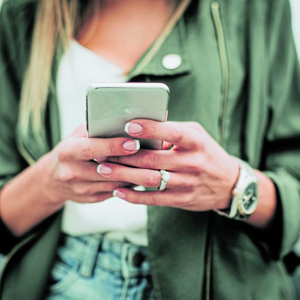 Woman hand typing in the mobile outside